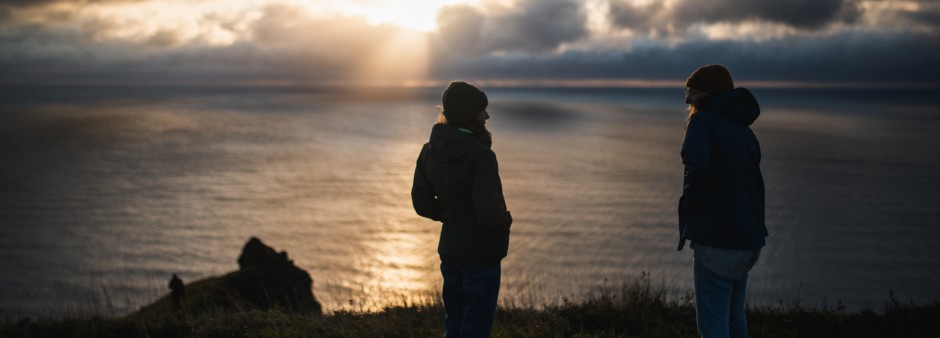 Deux personnes admirent un coucher de soleil près des falaises aux Îles de la Madeleine