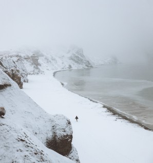 Personne qui marche en bordure de plage couverte de neige